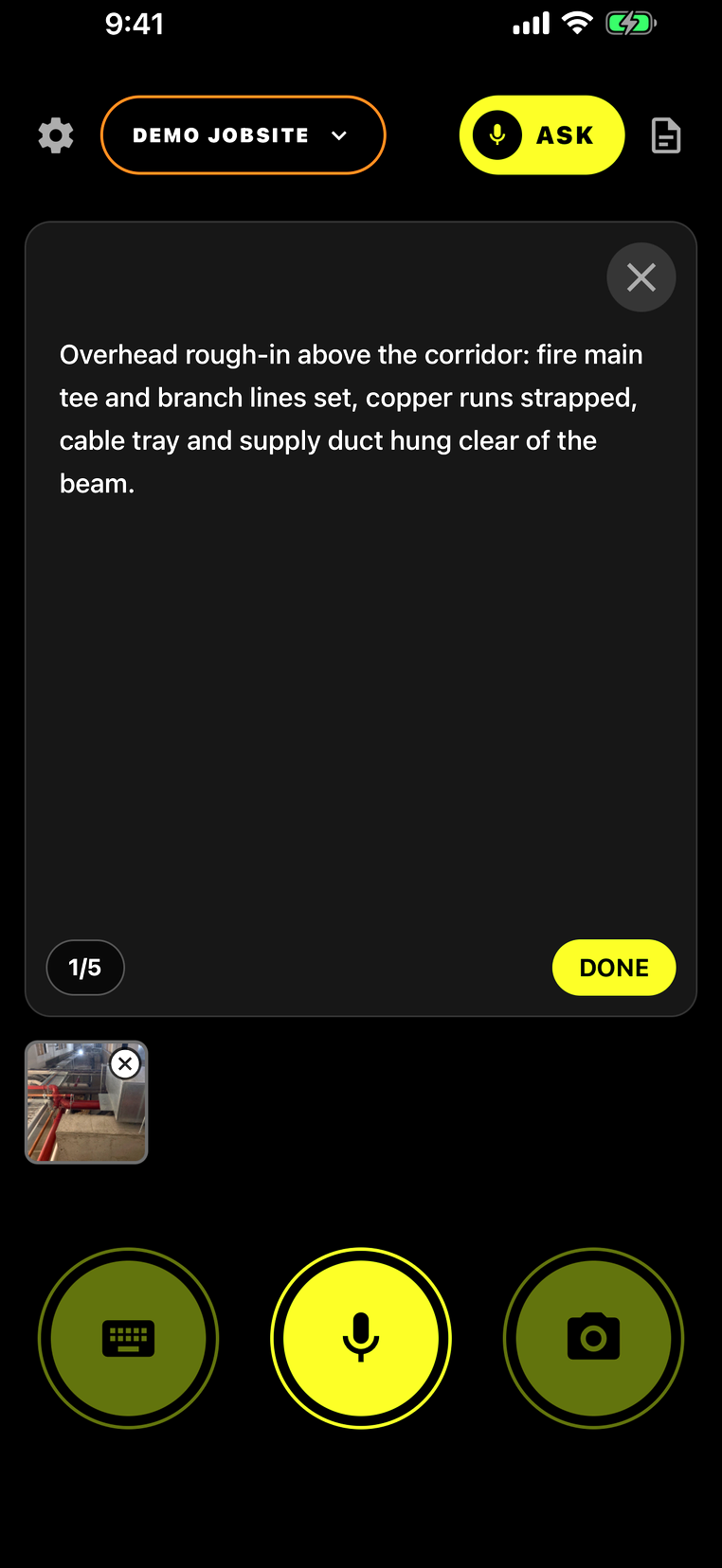 A voice-transcribed field note in SiteLog AI — 'Overhead rough-in above the corridor: fire main tee and branch lines set, copper runs strapped, cable tray and supply duct hung clear of the beam' — written clean and ready to file, with the red fire-main and ductwork photo attached and the mic button ready