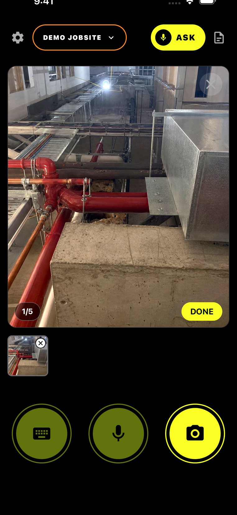 A full-size jobsite photo captured in SiteLog AI — red fire-main lines, copper runs, and overhead ductwork above a corridor rough-in